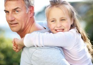 Closeup of cute young girl enjoying piggyback ride with her father - Outdoor